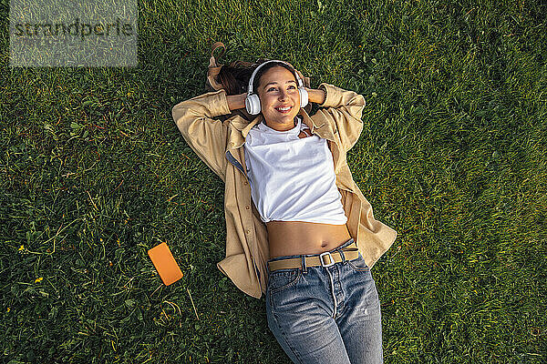 Smiling woman lying with hands behind head at park