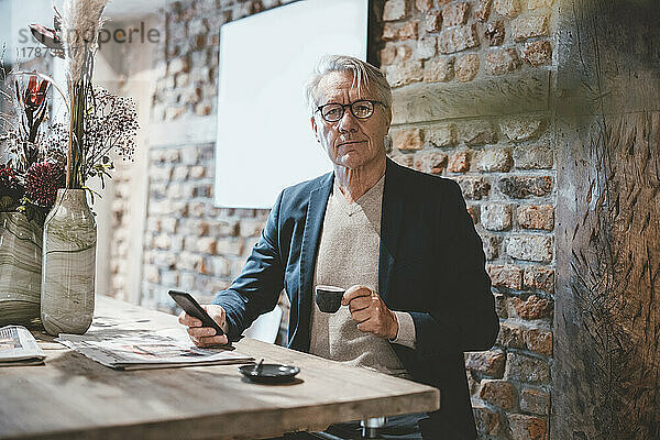 Geschäftsmann mit Smartphone beim Kaffee im Café
