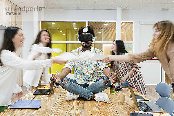 Geschäftsmann sitzt am Schreibtisch im Konferenzraum im Büro und trägt eine VR-Brille