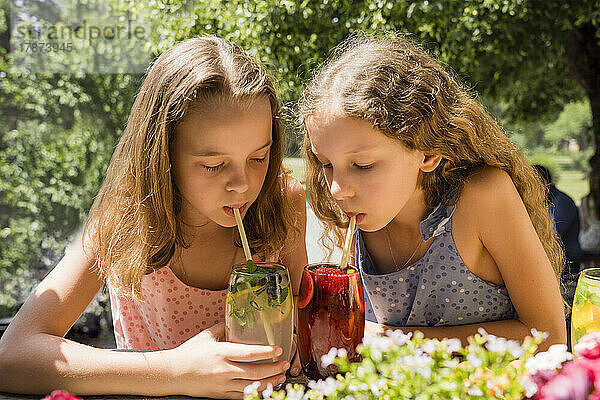 Mädchen mit Schwester trinkt Fruchtlimonaden