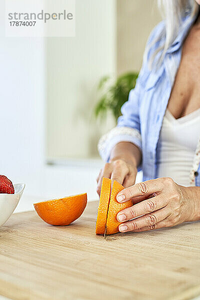 Frau schneidet Orangen in der Küche