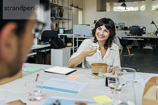 Lächelnde Geschäftsfrau mit Kollegen in der Pause im Büro