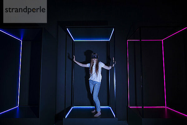 Mädchen mit Virtual-Reality-Headset steht neben beleuchteten Neonlichtern