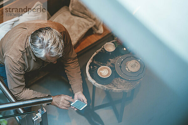 Älterer Mann schreibt Textnachrichten auf dem Smartphone im Café