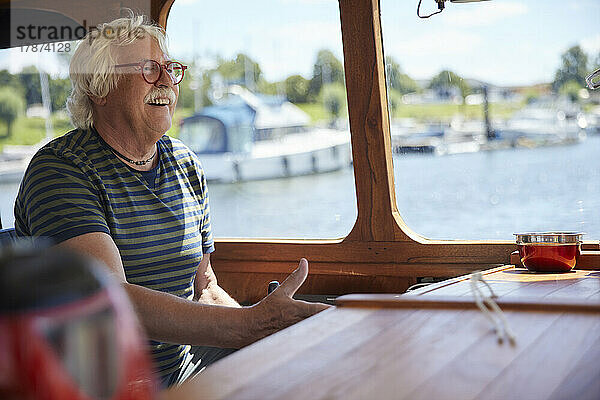 Happy senior man wearing eyeglasses sailing boat