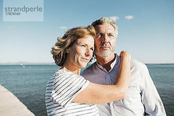 Lächelnde reife Frau mit Mann am Strand an einem sonnigen Tag