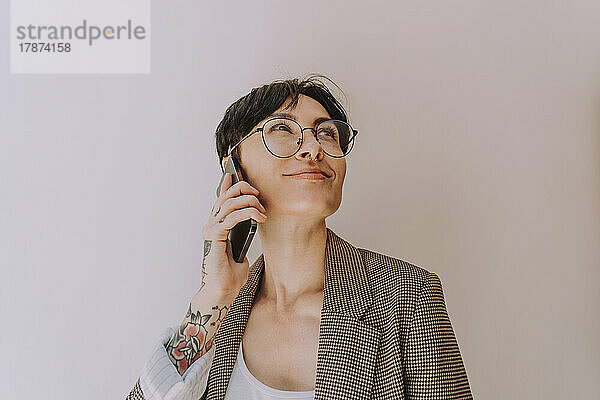 Lächelnde Geschäftsfrau telefoniert vor der Wand