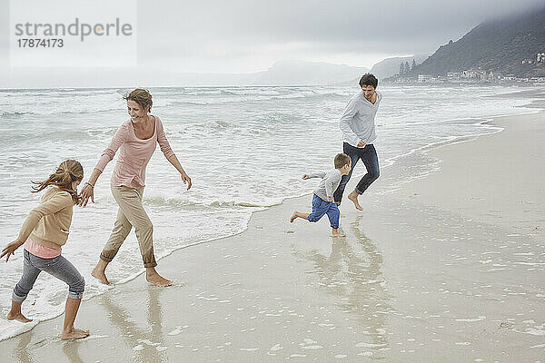 Eltern laufen mit Kindern am Strand