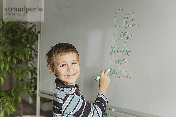 Smiling boy writing on whiteboard at home