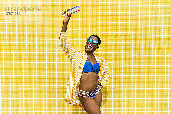 Fröhliche Frau im Bikini macht ein Selfie mit dem Smartphone