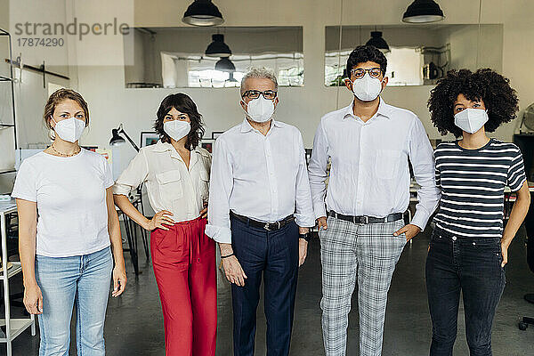 Kollegen mit Schutzmaske stehen zusammen im Büro