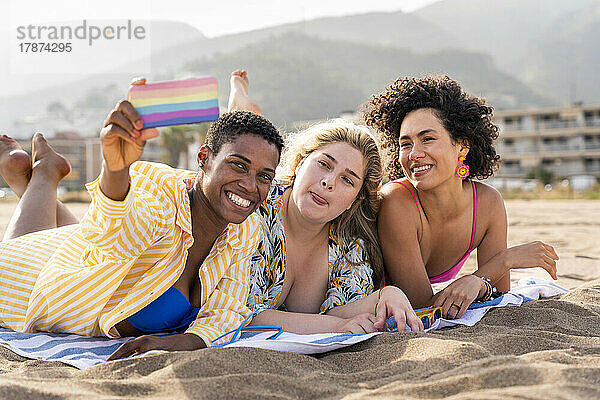Frau macht Grimasse und macht am Strand ein Selfie mit Freunden auf dem Smartphone