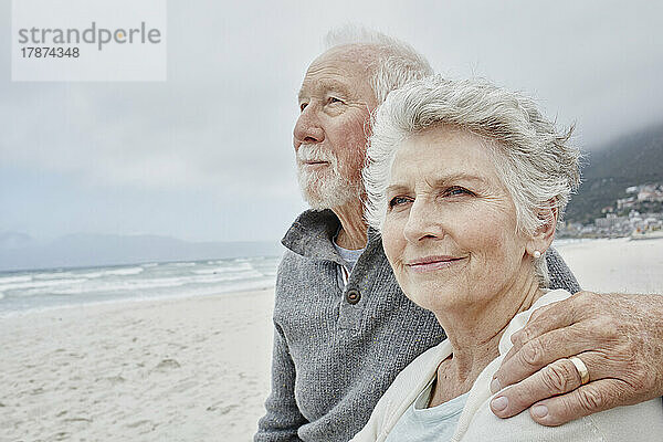 Älteres Paar steht mit Armen am Strand