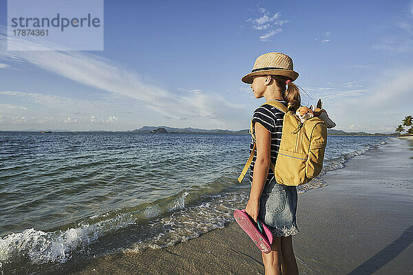 Mädchen mit Hut steht am Strand