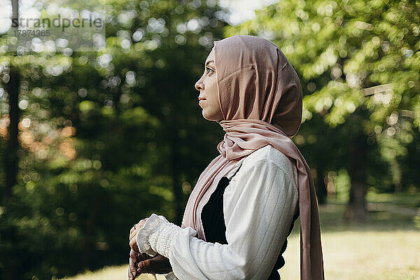 Junge Frau mit Hijab steht im Park