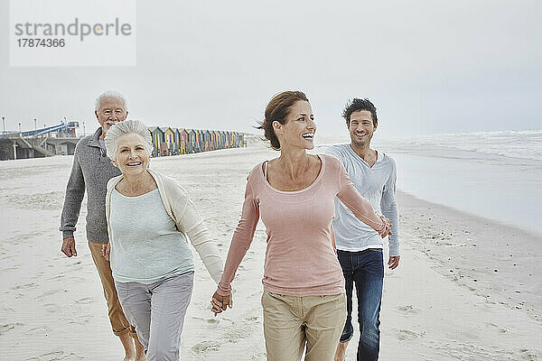 Erwachsenes Paar geht mit älteren Eltern am Strand spazieren