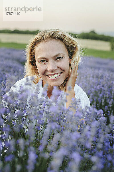 Glückliche Frau sitzt inmitten von Lavendelpflanzen