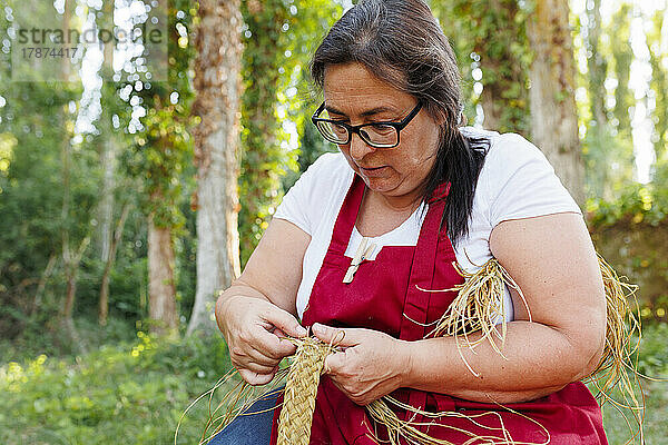Kunsthandwerkerin stellt im Garten Seil mit Espartogras her