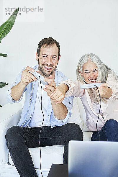 Glücklicher Mann mit Mutter  der zu Hause Videospiele genießt