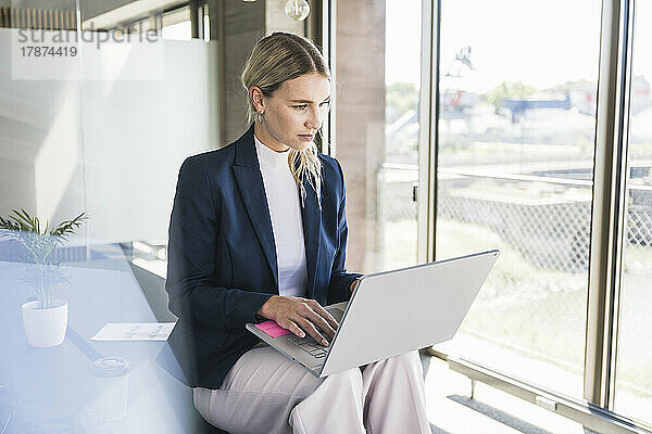 Geschäftsfrau trägt Blazer und arbeitet im Büro am Laptop