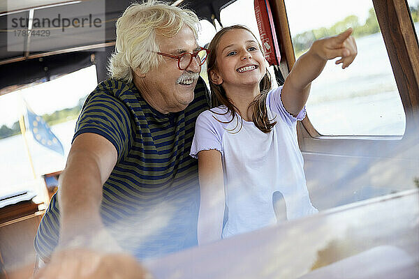 Aufgeregtes Mädchen zeigt auf Großvater im Boot