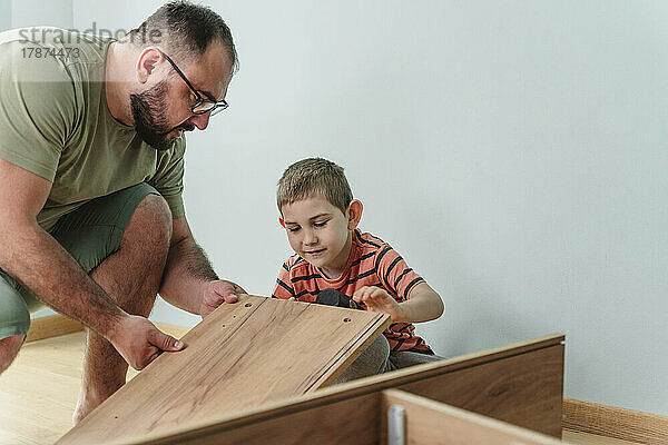 Vater und Sohn installieren Möbel zu Hause