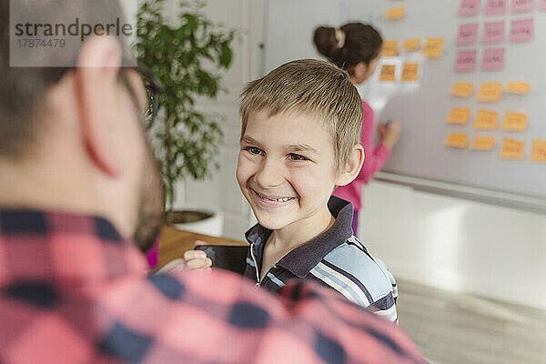 Lächelnder Junge  der den Lehrer beim Unterricht anschaut