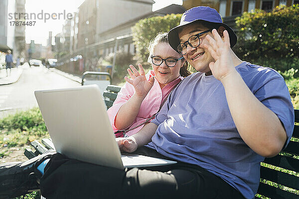 Lächelnder Bruder und Schwester winken bei Videoanruf über Laptop