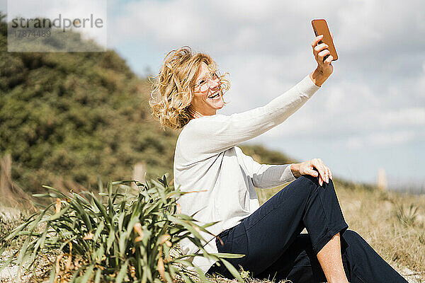 Glückliche reife Frau  die an einem sonnigen Tag ein Selfie mit dem Smartphone macht