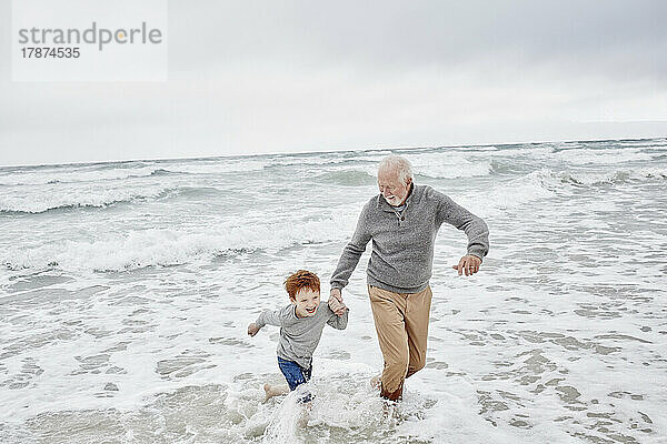 Grandfather playing with grandson at the sea