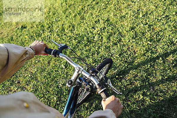 Hände einer Frau am Lenker  die im Park Fahrrad fährt