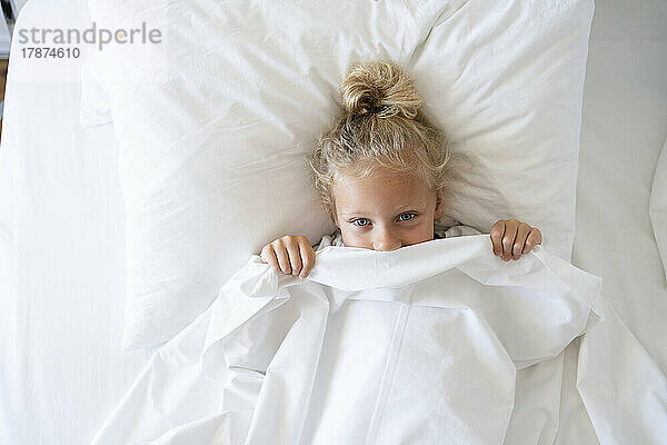 Mädchen guckt aus der Decke im Bett