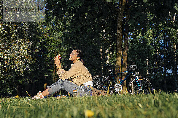 Glückliche Frau  die an einem sonnigen Tag im Park zu Mittag isst