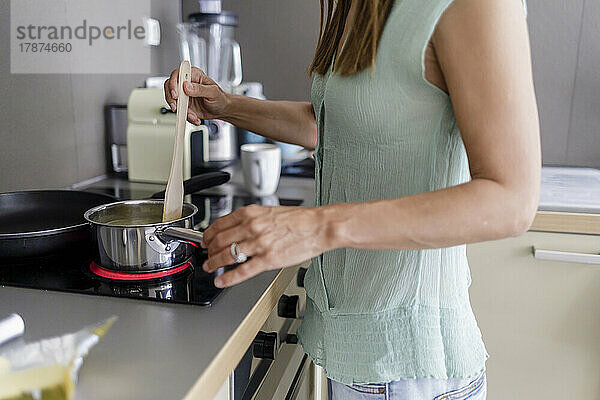 Reife Frau bereitet zu Hause in der Küche Essen zu