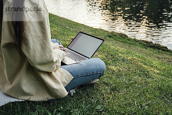 Freiberufler arbeitet am Laptop am See im Park