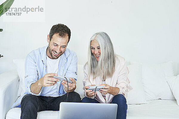 Happy mother with son playing video game on laptop