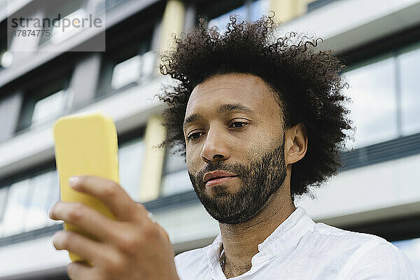 Mann mit lockigem Haar benutzt Mobiltelefon