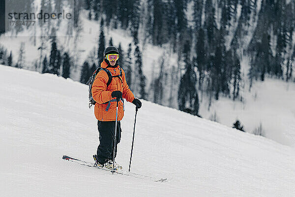 Skifahrer mit Helm und Schutzbrille steht auf Schnee