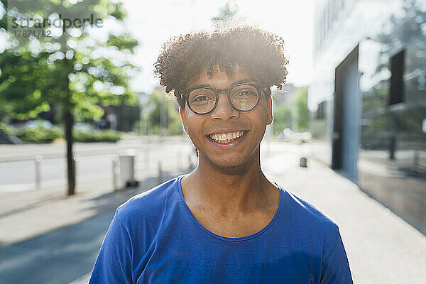 Glücklicher junger Mann mit Brille an einem sonnigen Tag