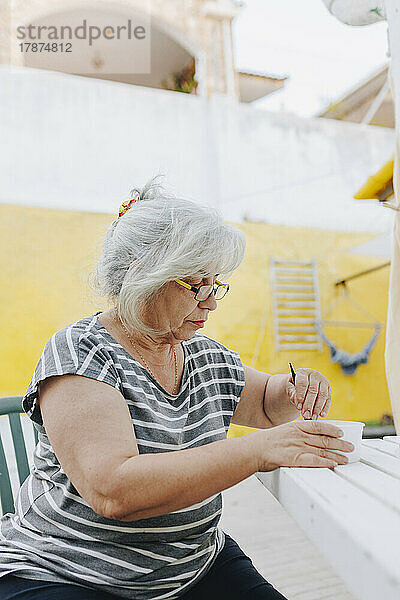Ältere Frau bereitet Haarfärbemittel in einer Schüssel auf dem Tisch vor