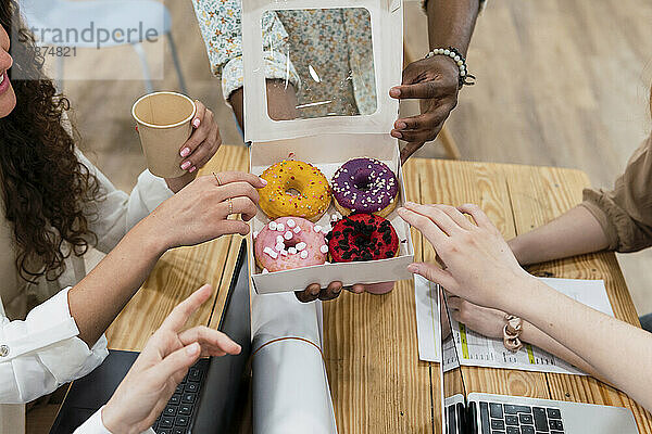 Geschäftsmann überreicht Donuts an Kollegen im Büro