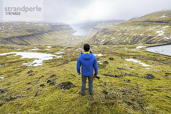 Männlicher Wanderer mit Blick auf den Kaldbaksfjördur-Fjord