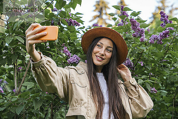 Glückliche Frau  die im Park ein Selfie mit ihrem Smartphone macht