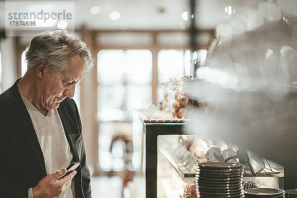 Geschäftsmann mit Smartphone im Café