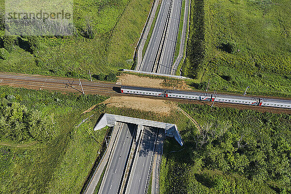 Luftaufnahme eines Personenzuges  der über eine Eisenbahnüberführung fährt