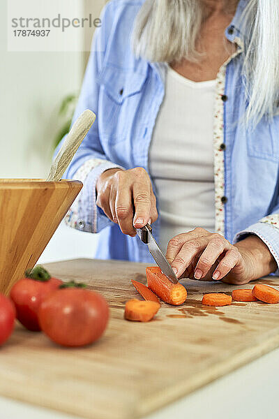 Frau schneidet Karotten in der Küche