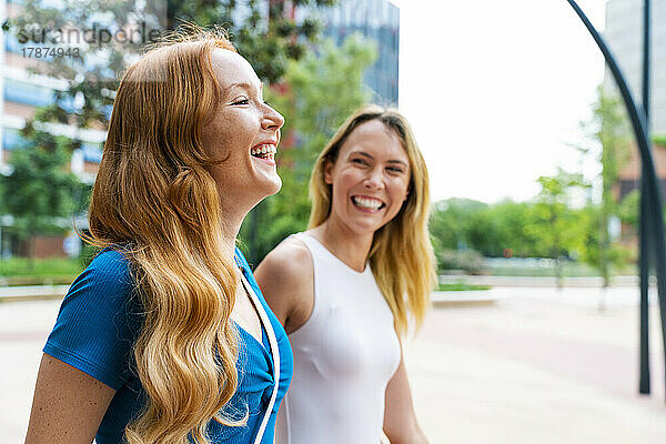Lächelnde Frau geht mit Freundin am Fußweg spazieren