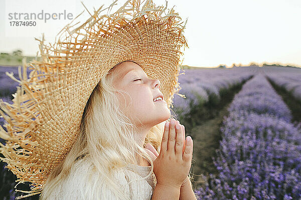 Lächelndes Mädchen mit geschlossenen Augen  das im Lavendelfeld betet