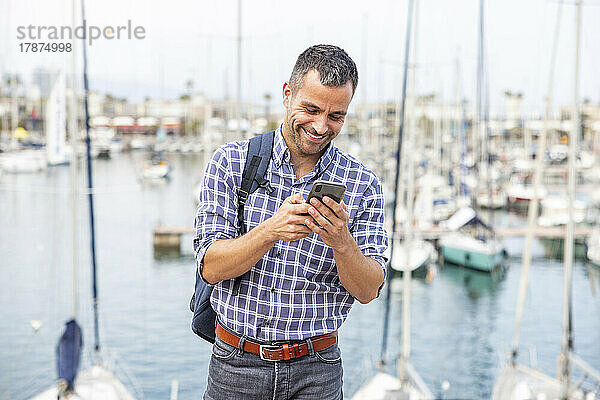 Glücklicher reifer Mann  der im Hafen sein Mobiltelefon benutzt