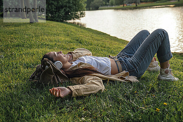 Frau liegt im Gras am See im Park